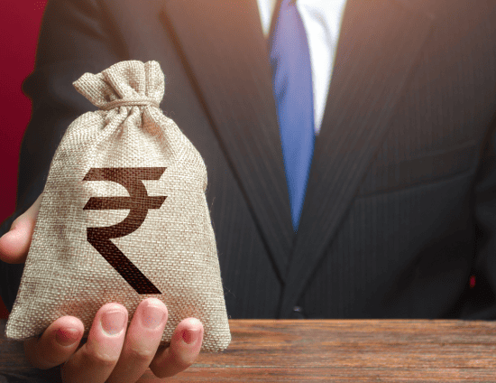 A businessman holding a burlap money bag featuring the Indian Rupee symbol.